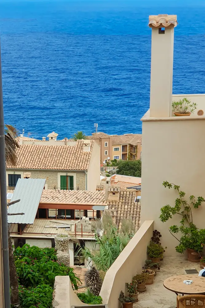 Malerische mediterrane Architektur in Banyalbufar, Mallorca, mit Blick auf das tiefblaue Meer und traditionelle Ziegeldächer, umgeben von üppigem Grün.